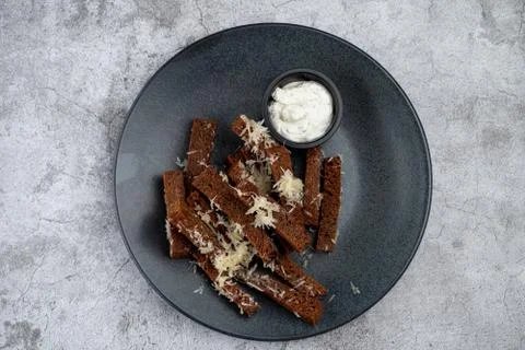 Deep fried rye croutons with grated parmesan cheese and garlic sauce on grey  Foto stock
