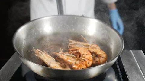 Deep fried shrimps being prepared on frying pan. Chef tossing, mixing and Stock Footage 122118920