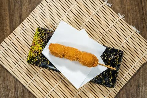 Deep fried skewer breadcrumb crispy bamboo mat black plate Stock Photos
