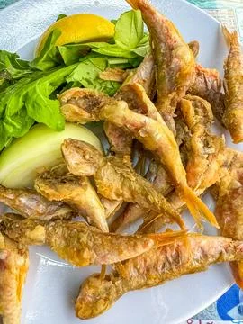 Deep fried small fish in white plate with onion and lemon Stock Photos