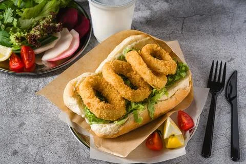 Deep fried squid in bread with greens on the side. Squid sandwich Stock Photos