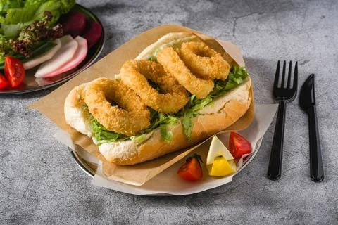 Deep fried squid in bread with greens on the side. Squid sandwich Stock Photos