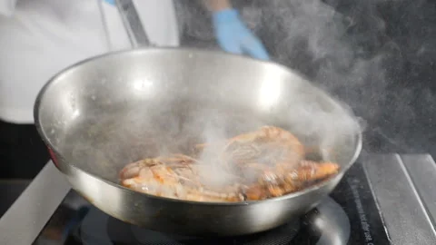 Deep fried tiger shrimps preparing on frying pan. Chef tossing, mixing and Stock Footage 114412386