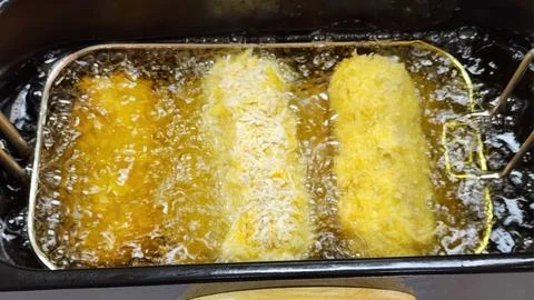 Deep Frying Breaded Crispy Snacks in Boiling Oil in Professional Fryer Stock-Fotos