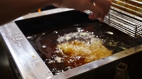 Deep frying breaded meat portions in hot oil inside a restaurant kitchen Stock Footage 345930371