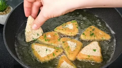 Deep frying breaded potato triangles in hot oil for a crispy golden brown snack Stock Footage 325071878