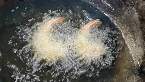 Deep-frying breaded shrimp in hot boiling oil in a wok pan Stock Photos