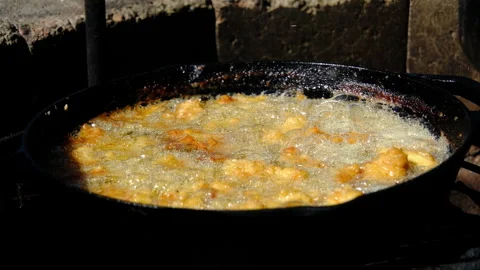 Deep frying catfish nuggets or fish in batter and breadcrumbs in cast iron pan Stock Footage 289178922