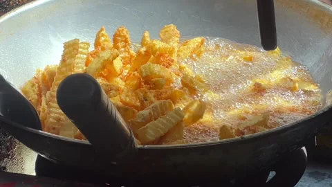 Deep frying crinkle cut potato fries in a wok 動画素材 339531222