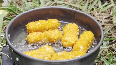 Deep frying crispy nuggets in hot oil outdoor camping pan Stockbeeldmateriaal 347010487