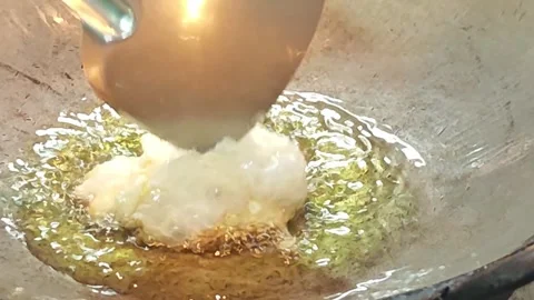 Deep frying egg white in hot bubbling oil inside a wok. Vídeo Stock 343697903