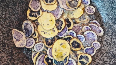 Deep frying native Peruvian purple potato slices in hot oil. 動画素材 339078722