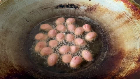 Deep Frying Small Pink Meatballs or Sausages in Hot Cooking Oil Stock Footage 340897707