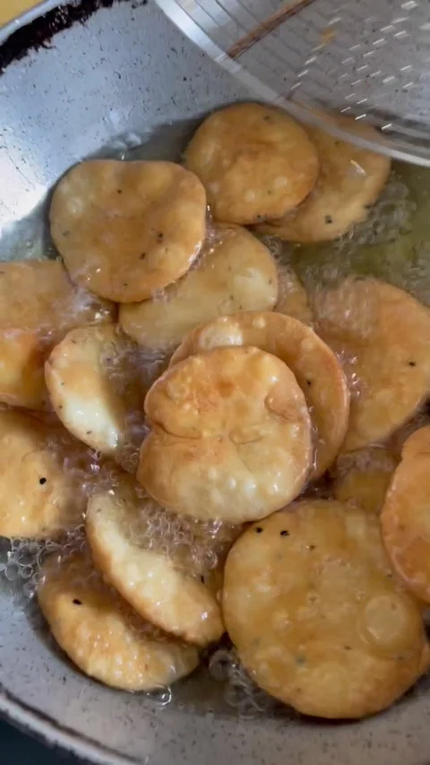 Deep frying a snack made with whole wheat flour called mathri or matthi in oi Stock Footage 338373614