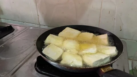Deep frying tofu on a pan in the kitchen. Stock Footage 242381948