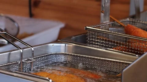 Deep-frying traditional Asian snack - corn dog, breadcrumbs sausages. Boiling Stock Footage 303352425