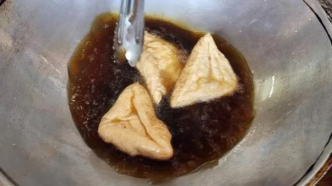 Deep Frying Triangular Tofu Puffs in a Metal Wok for Traditional Asian Cuisin Stock-Fotos