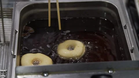 Deep frying uncooked donuts in oil Stock Footage 307339985