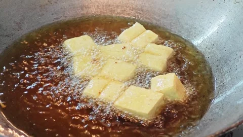 Deep frying white tofu cubes inside a metal wok. 動画素材 344556438
