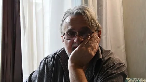 Deep gaze of an elderly man against the background of a bright window. Stock Footage 298609709