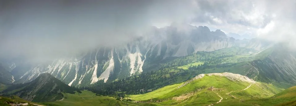 Deep hanging clouds above mountains. Mystic light breaks through fog. Stock Photos