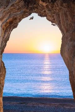 Deep high Cave on Seafront and extreme Climbers on Sunrise Stock Photos