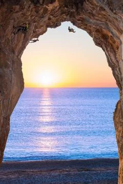 Deep high Cave on Seafront and extreme Climbers on Sunrise Stock Photos