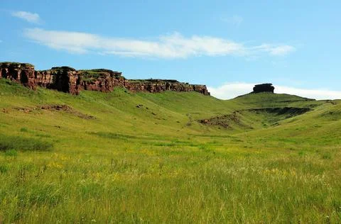 A deep hollow between high hills and stone formations on the peaks. Stock Photos