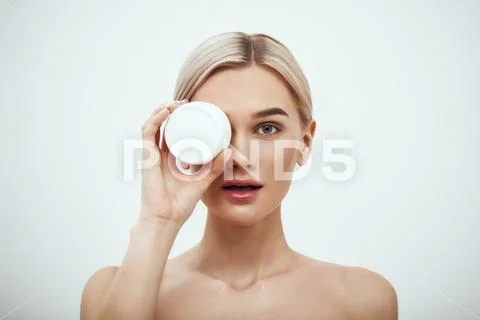 Deep hydration. Portrait of cute young blonde woman showing face cream while Stock Photos