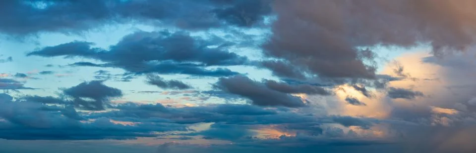 Deep indigo storm clouds hang against the horizon in the rays of the setting sun Stock Photos