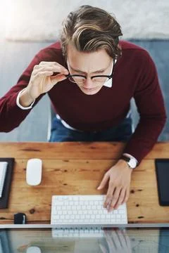 Deep in the make it happen zone. High angle shot of a young man using a computer Stock Photos