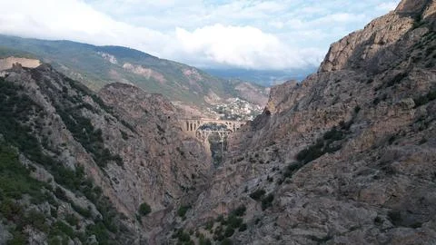 Deep mountain gorge with a distant valley town far below rocky walls, Stock Photos