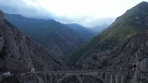 Deep mountain gorge with steep rocky walls and valley floor under overcast sky Stock Footage 342705987