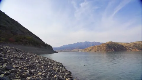 A deep mountain lake surrounded by rocks on a cloudy day Stock Footage 247616349
