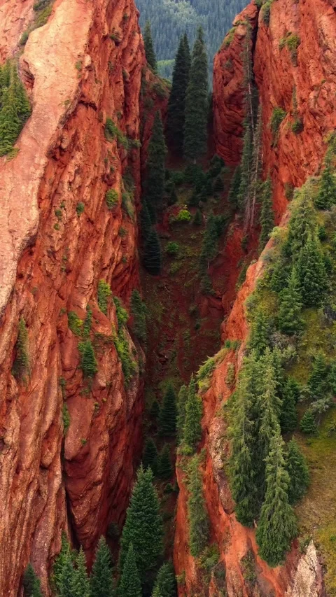 Deep narrow chasm between Seven Bulls red rock pillars in Kyrgyzstan Stock Footage 344651823