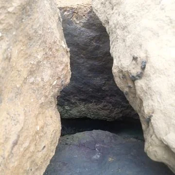 Deep narrow crevice between two large weathered coastal rocks water Stock Photos