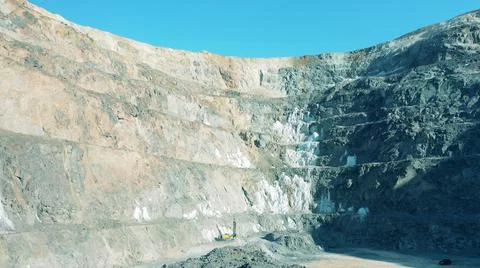 Deep open-pit mine with a drilling machine working in it Photos