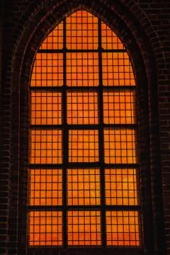 Deep orange light coming from a Gothic window conveys diabolic, hellish feelings Stock Photos