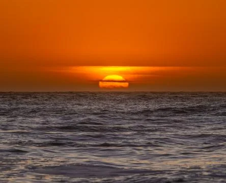 Deep Orange Sun Sinks Into The Clouds And Pacific Ocean Stock Photos