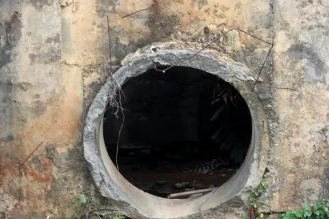 Deep perspective inside a large concrete drainage pipe tunnel leading to bri Stock Photos