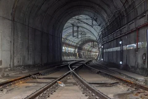 A deep perspective shot of train tracks curving through a long, illuminated c Stock Photos