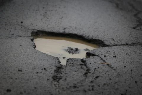 Deep potholes in an old road in need of maintenance Stock Photos
