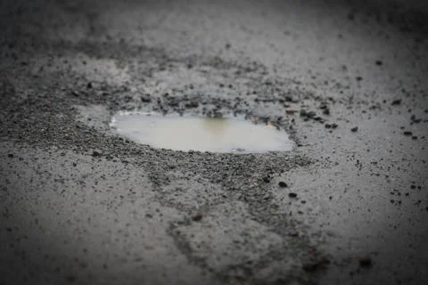Deep potholes in an old road in need of maintenance Stock Photos