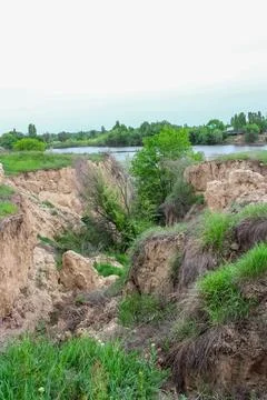 A deep ravine with eroded clay cliffs overlooking a scenic lake. Green gras.. 写真素材