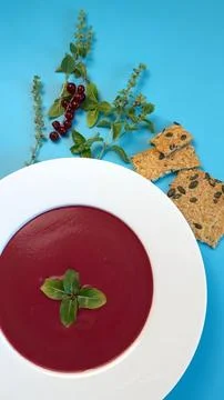Deep red beetroot soup contrasts with golden crackers and blue hues. Bold colors Stock Photos