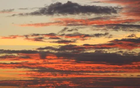 Deep red clouds and warm colored sky at sunset Stock Photos