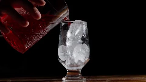 Deep Red Cocktail Poured Over Ice into Chilled Glass Stock Footage 337862490