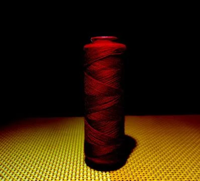 Deep red color sewing thread with dark background. Stock Photos