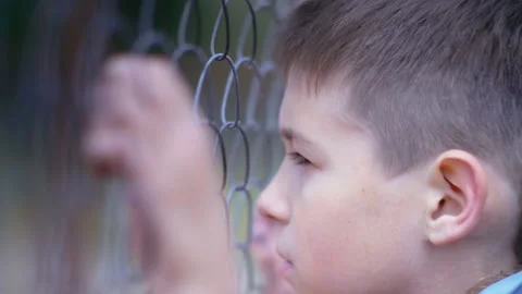 Deep Regret and Reflection: Close-Up of a Sad Boy Leaning on a Fence, Remorseful Video stock 253124974