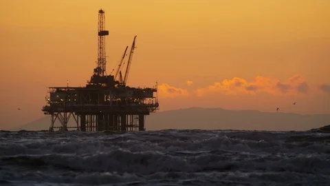 Deep sea offshore Industrial oil drilling platform in silhouette at sunset Stock Footage